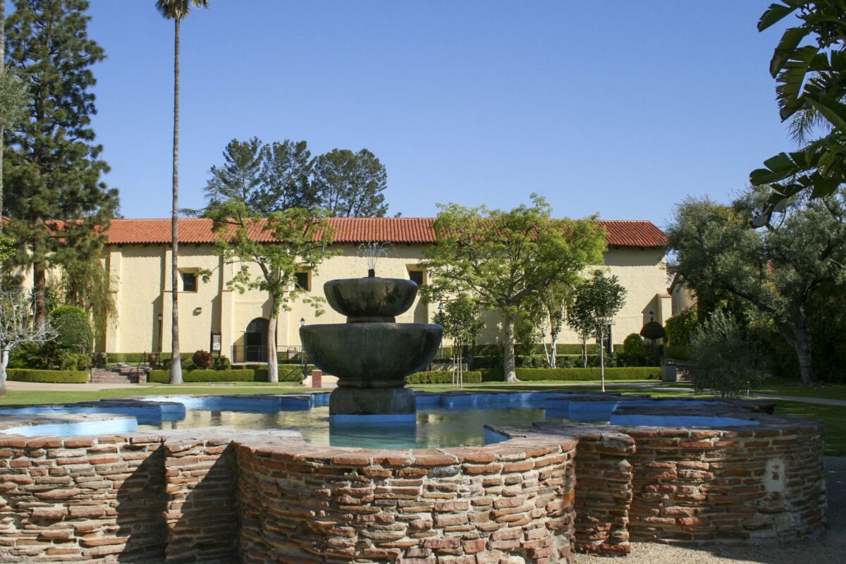 A stone-walled fountain in front of an adobe building