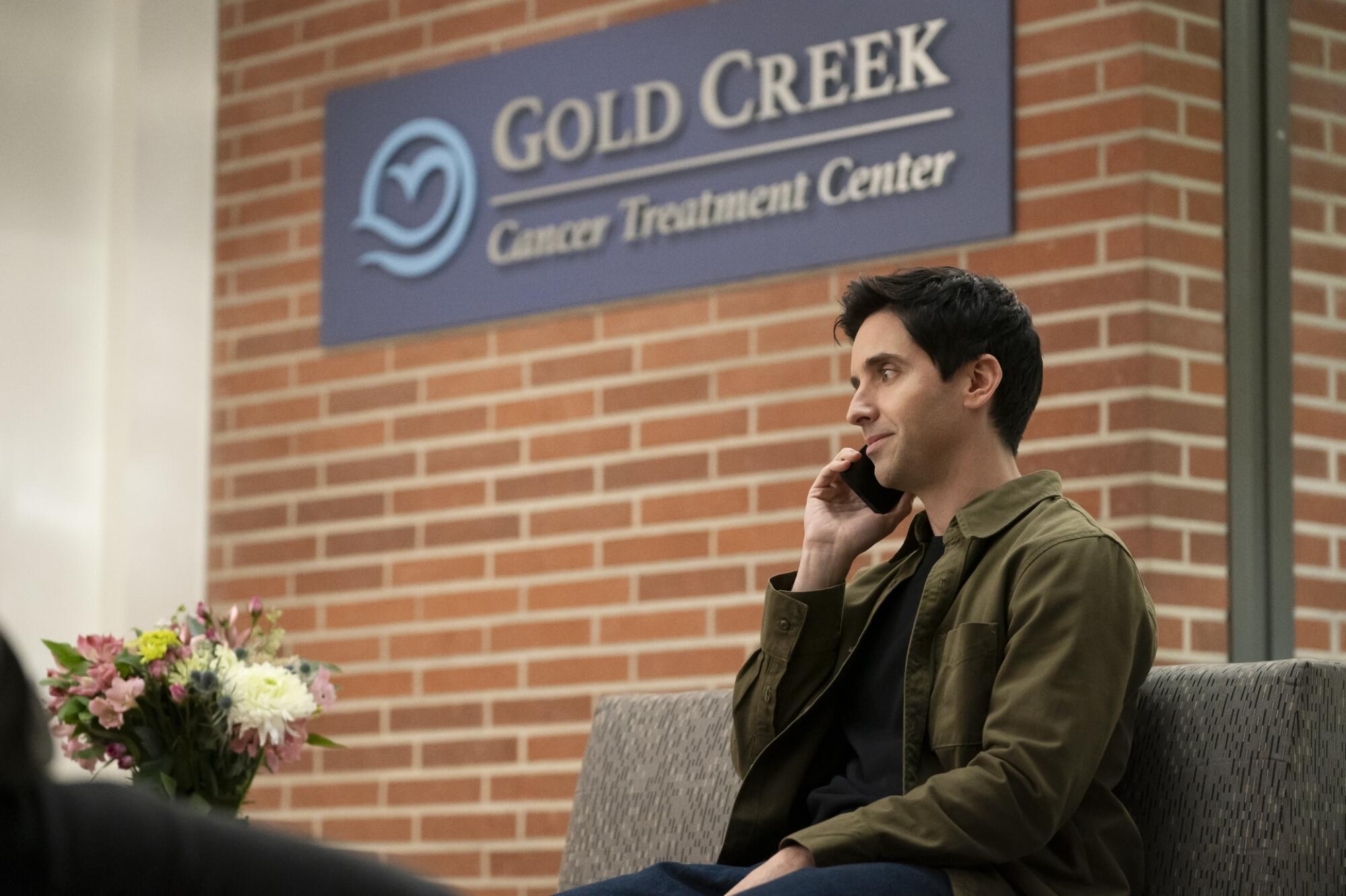 A man on a cellphone in a cancer treatment center waiting room.