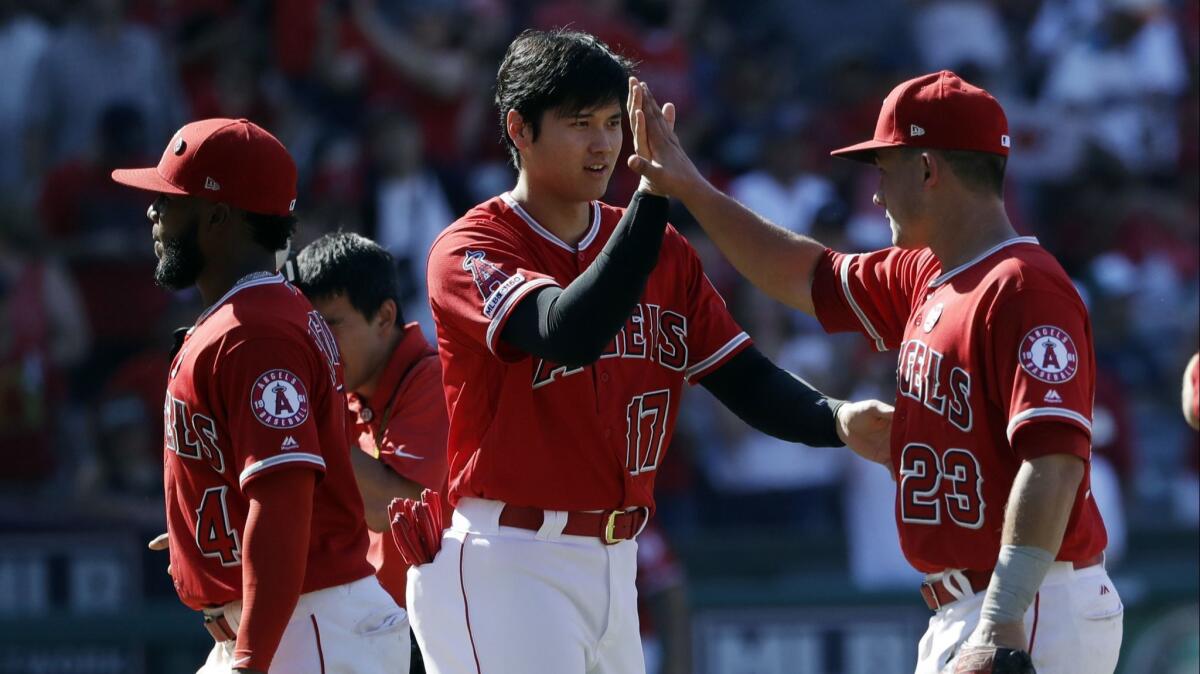 Shohei Ohtani, middle, celebrates with Angels teammate Matt Thaiss following Sunday's win over the Mariners.