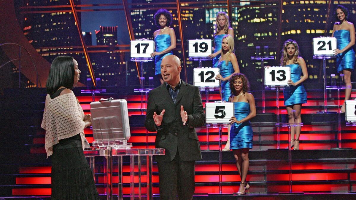 Models behind host Howie Mandel hold numbered brief cases that contain various amounts of money.
