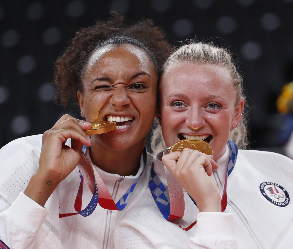 U.S. volleyball players Jordan Thompson and Jordyn Poulter bite their gold medals.