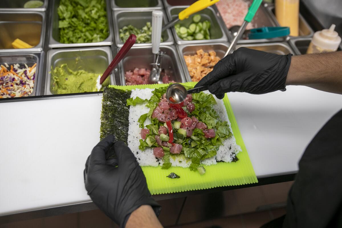 Omar Flores makes a Geisha Burrito from Sushirrito at Local Kitchens in Huntington Beach.