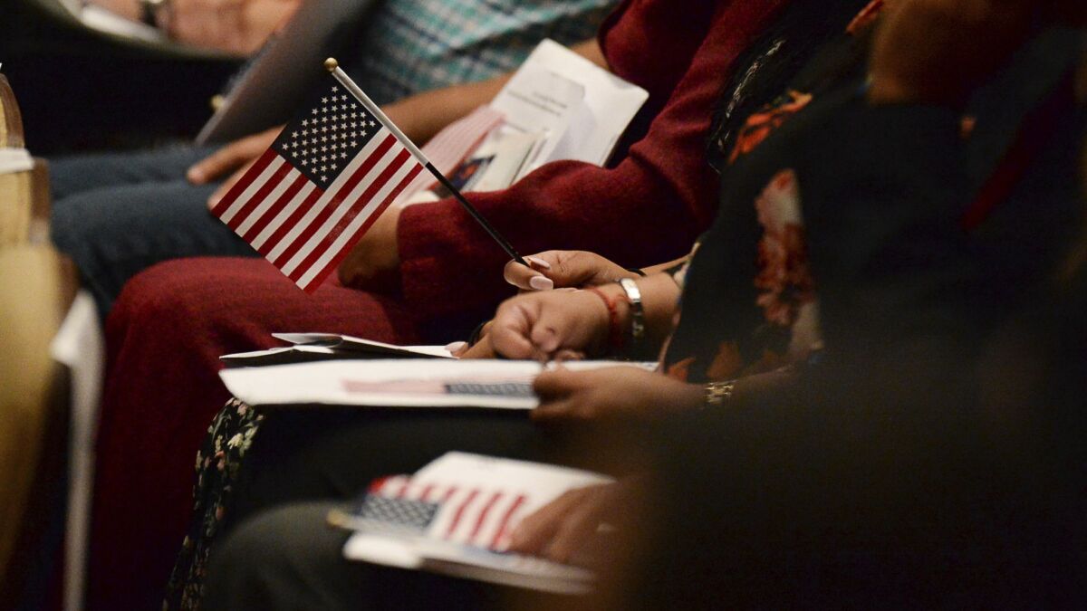Immigrants sit at a naturalization ceremony. In the bribery case, federal officers approved applications of ineligible immigrants to become naturalized citizens and received $1,000 per immigrant, officials said.