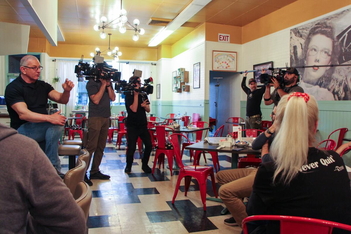 Chef Robert Irvine, left, speaks to employees of Rosie's Cafe in Escondido during filming of an episode of "Restaurant: Impossible" in February. The episode, where Irvine returned to host a fundraising carnival for injured Rosie's owner Kaitlyn Pilsbury, will air on Food Network on May 28.