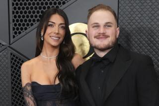 Brianna LaPaglia, left, and Zach Bryan arrive at the 66th annual Grammy Awards