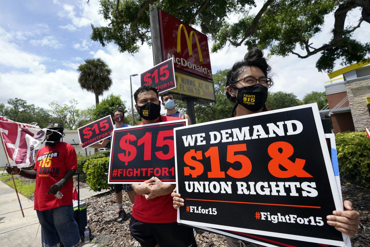 Picketers hold signs demanding higher wages in front of a McDonald's