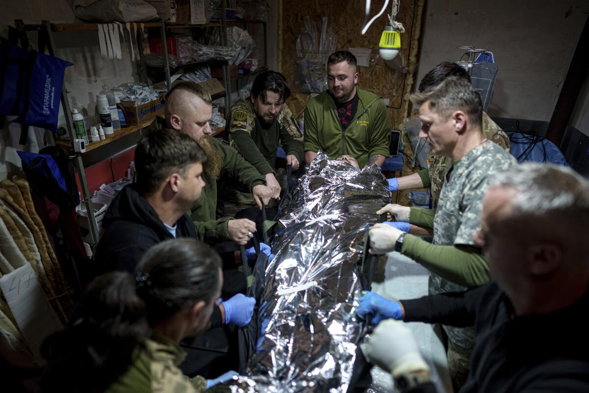 Ukrainian military medics shift an injured comrade to a stretcher.