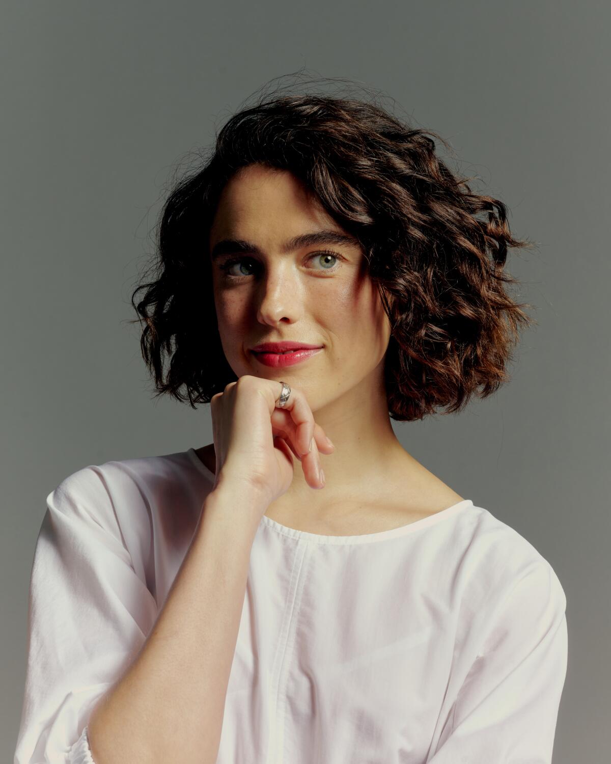 Margaret Qualley poses with her hand under her chin.