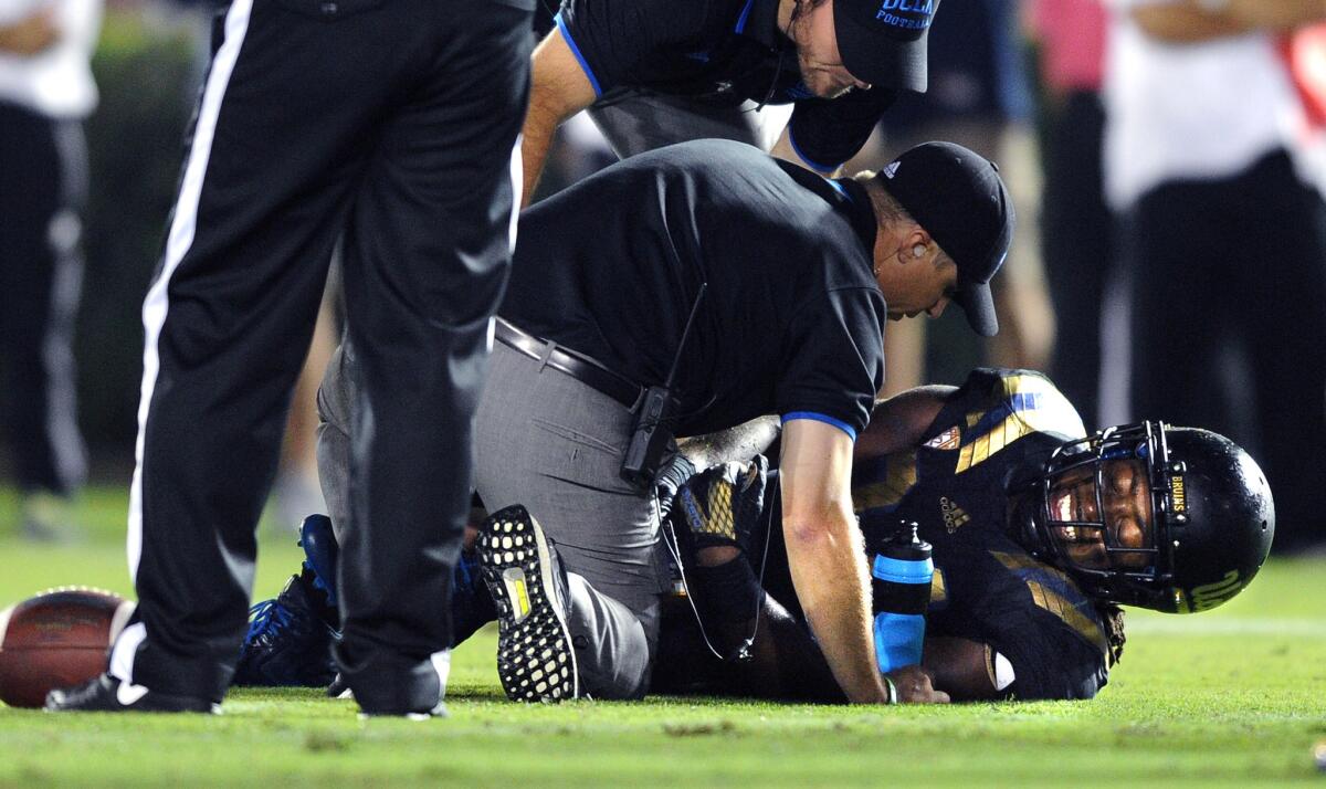 UCLA running back Paul Perkins is checked by a trainer after injuring a knee in the second quarter.