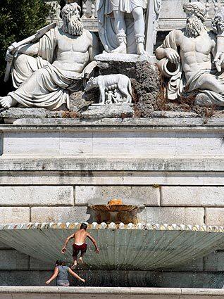 Children play in the Goddess of Rome fountain as temperatures in the Italian capital climbed into the 90s.