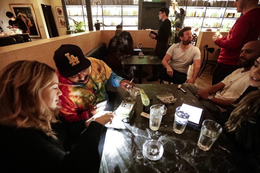 Five people seated at a table in a cannabis consumption lounge.