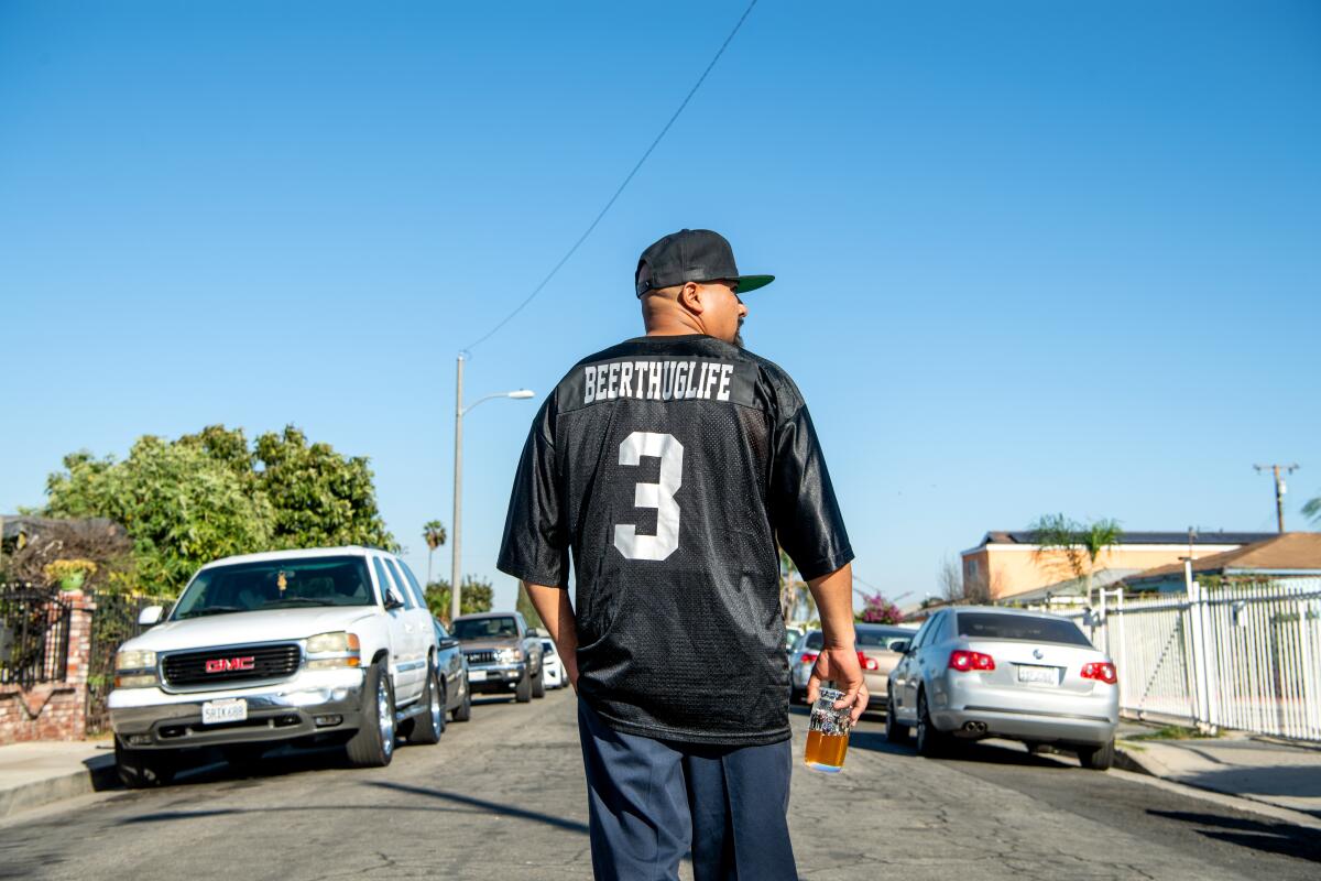 Edgar Preciado stands in the middle of a street, back to the camera, in a No. 3 black football with "BEERTHUGLIFE" on the nameplate.