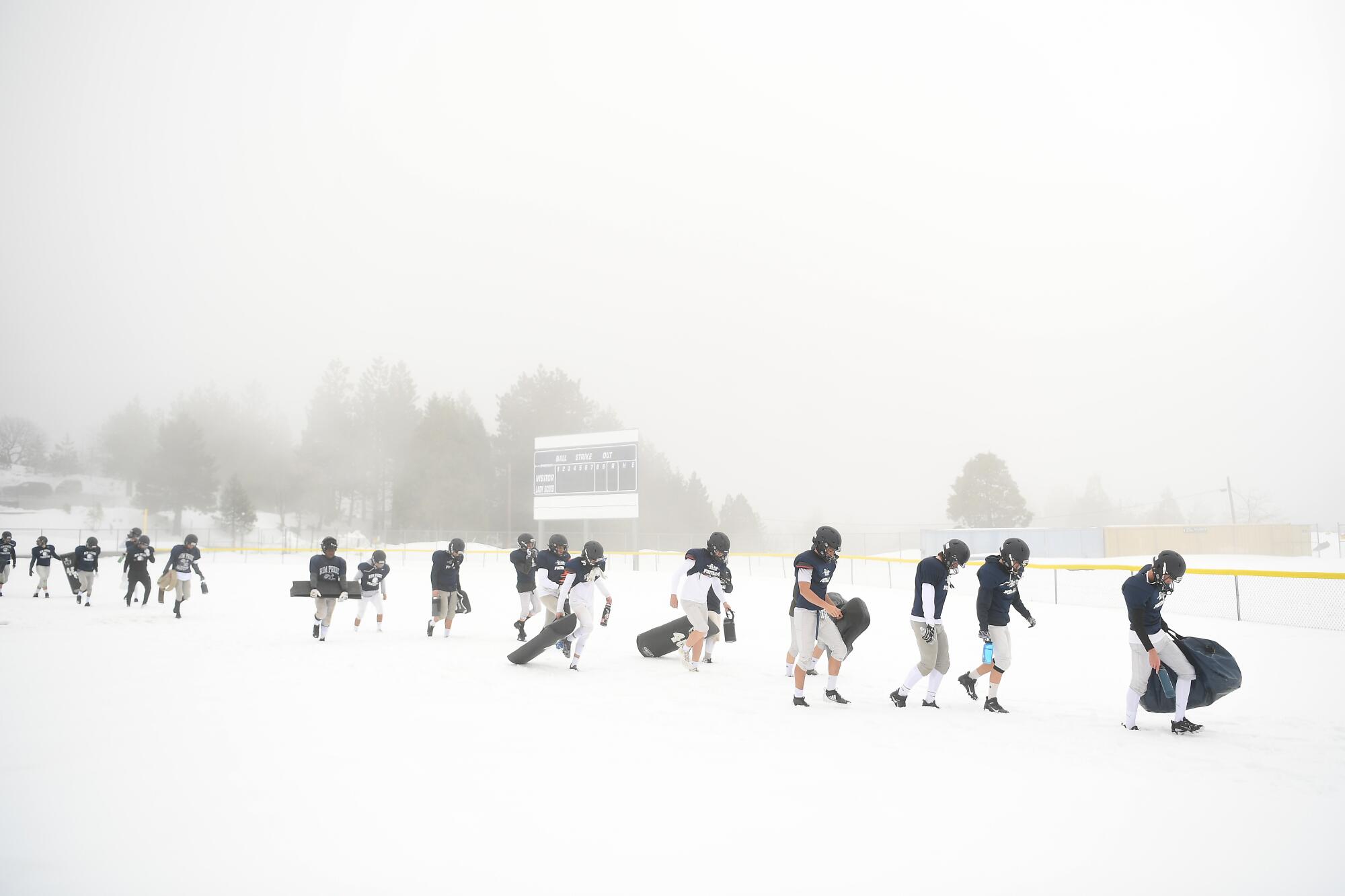 Rim of the World High School football players walk to the practice field after a snowstorm in Rimforest on Tuesday.