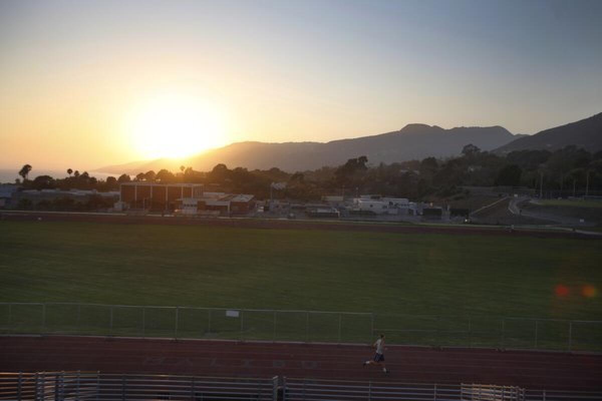 At sunset, a runner makes his way around the Malibu High School track in July. Preliminary testing at the school has uncovered elevated levels of toxins, district officials said.