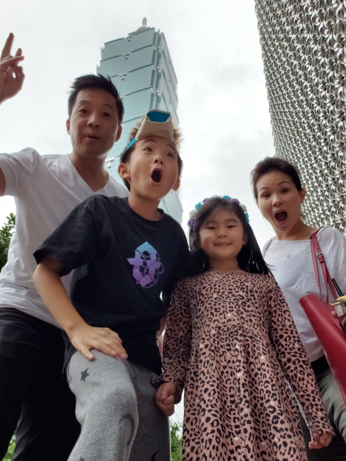 A man, woman and two children pose in front of a skyscraper.