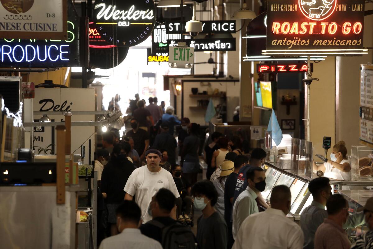 People, many of them masked, wait for lunch at the Grand Central Market in downtown Los Angeles on June 15.