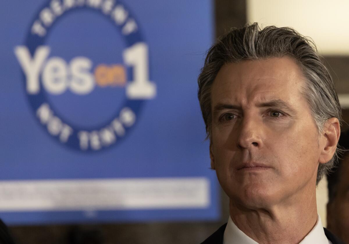 Gavin Newsom in front of sign that reads "Yes on 1"