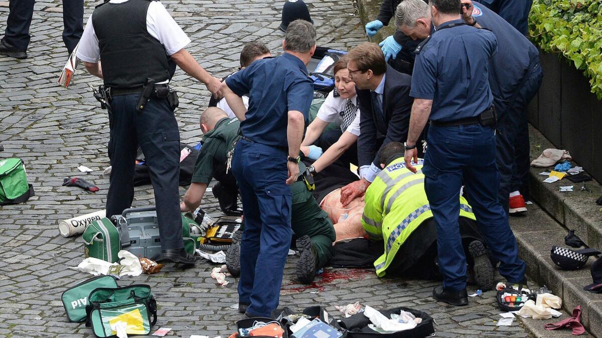 Conservative member of Parliament Tobias Ellwood, center, helps emergency services attend to an injured person outside the Houses of Parliament in London on March 22, 2017.