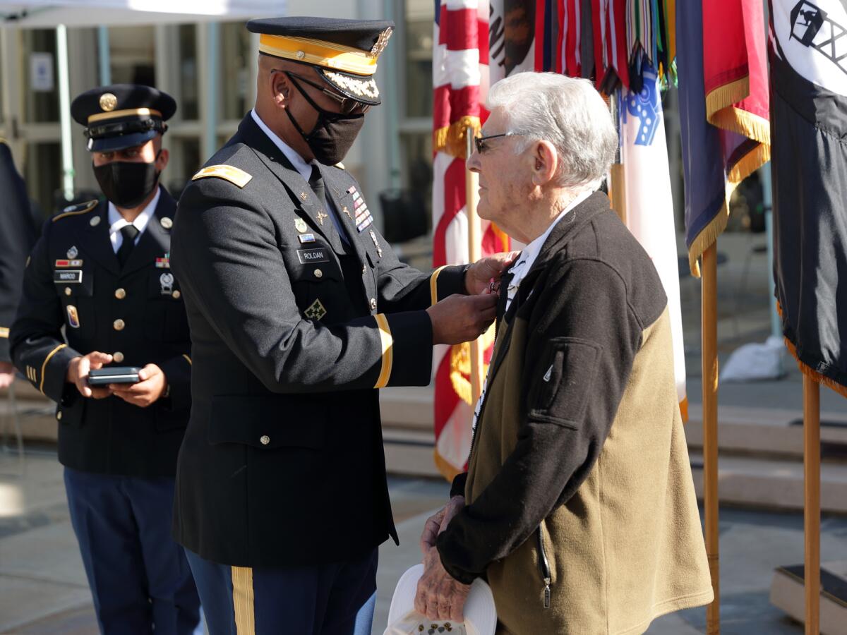 Col. Gilbert Roldan (Chief of Staff, US Army 40th Infantry Division) pins the Bronze Star medal on honoree Bob Baker