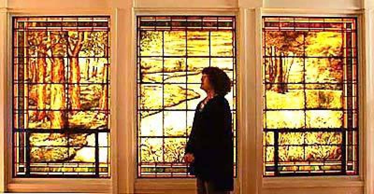 Patricia Knop stands before a triptych of windows salvaged from an early Greene & Greene house in Pasadena. They are among two dozen stained-glass panels throughout the Santa Monica house.