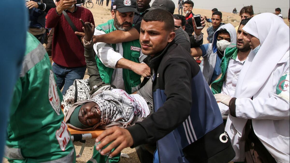 Palestinian paramedics carry away a woman who was injured during clashes with Israeli forces on the border between the Gaza Strip and Israel.