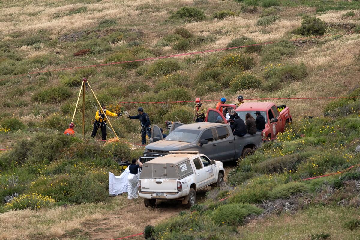 Several people with vehicles work in a water hole where human remains were found 
