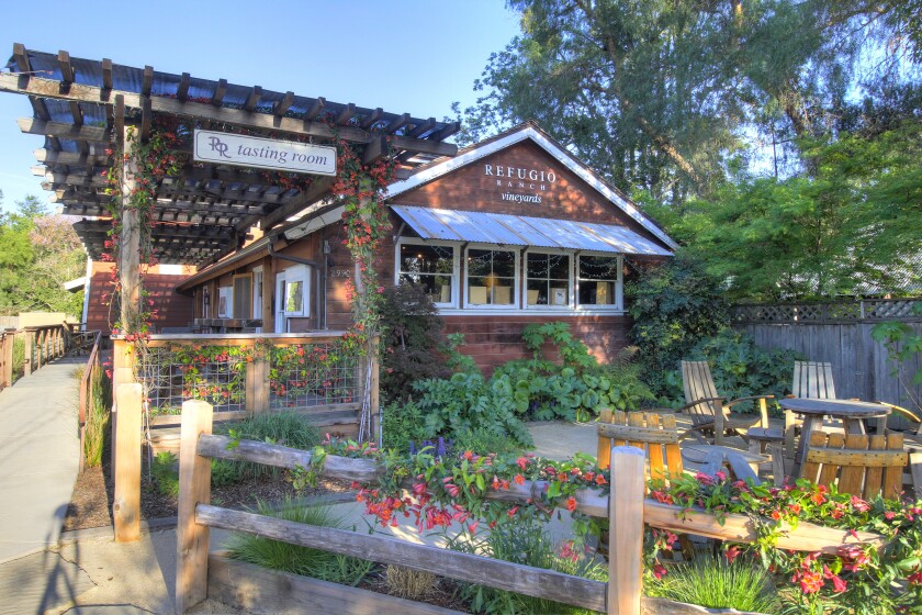 A cottage-like building with a flower-covered wooden fence in front of it