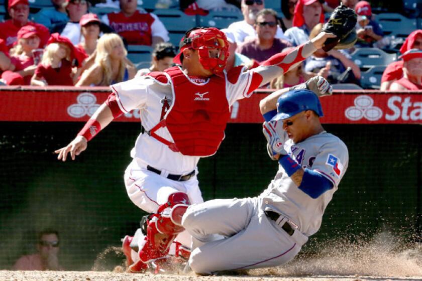 Rangers center fielder Leonys Martin slides safely past Angels catcher Hank Conger to score a run in the seventh inning Sunday afternoon in Anaheim.