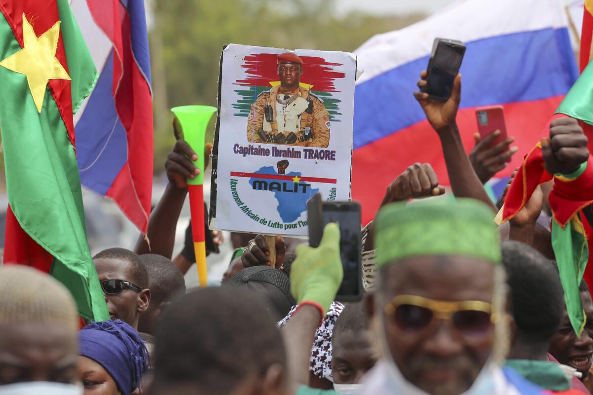 Supporters of Burkina Faso's latest coup leader Capt. Ibrahim Traore gather outside the National Assembly waving Burkina and Russian flags as Traore was appointed Burkina Faso's transitional president in Ouagadougou, Burkina Faso, Friday Oct. 14, 2022. (AP Photo/Kilaye Bationo)