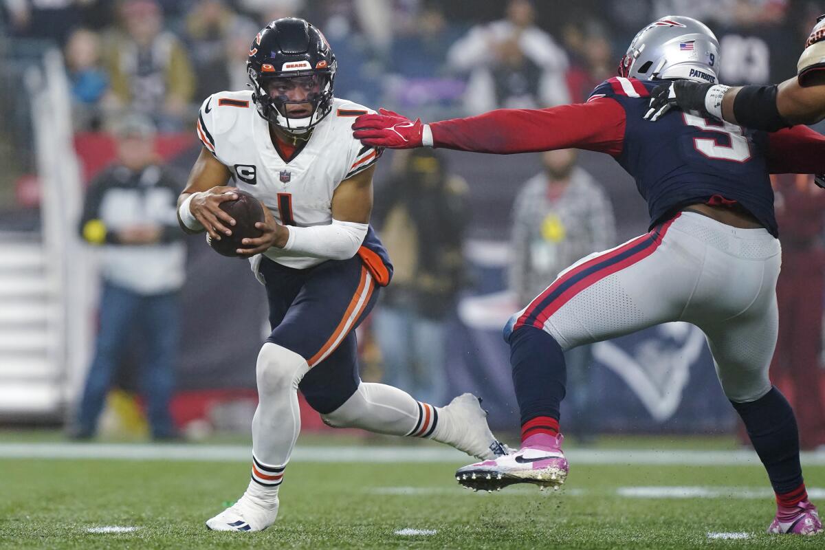 Chicago Bears quarterback Justin Fields eludes New England Patriots linebacker Matthew Judon.