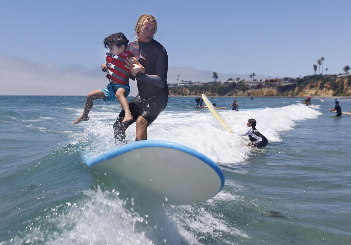 Volunteer instructor Ashton Pignat surfs with Joey Rohloff, 5, during the Surfers Healing camp at Tourmaline Beach.