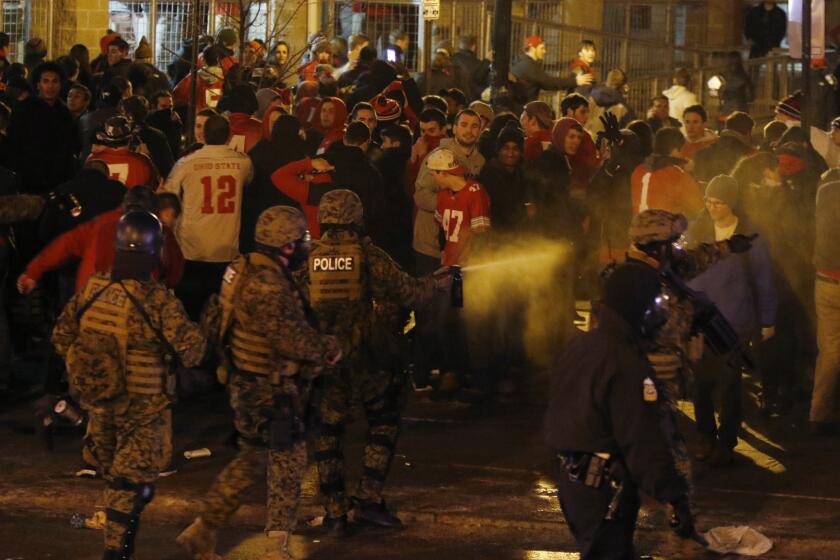 Police officers use pepper spray to disperse a crowd of Ohio State fans in Columbus, Ohio, as they celebrate the Buckeyes' 42-20 win over Oregon in the college football national title game on Monday.