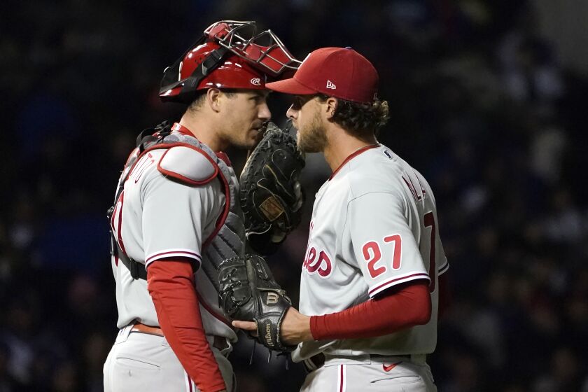 Philadelphia Phillies catcher J.T. Realmuto talks with starting pitcher Aaron Nola during the fifth inning of a baseball game against the Chicago Cubs Wednesday, Sept. 28, 2022, in Chicago. (AP Photo/Charles Rex Arbogast)