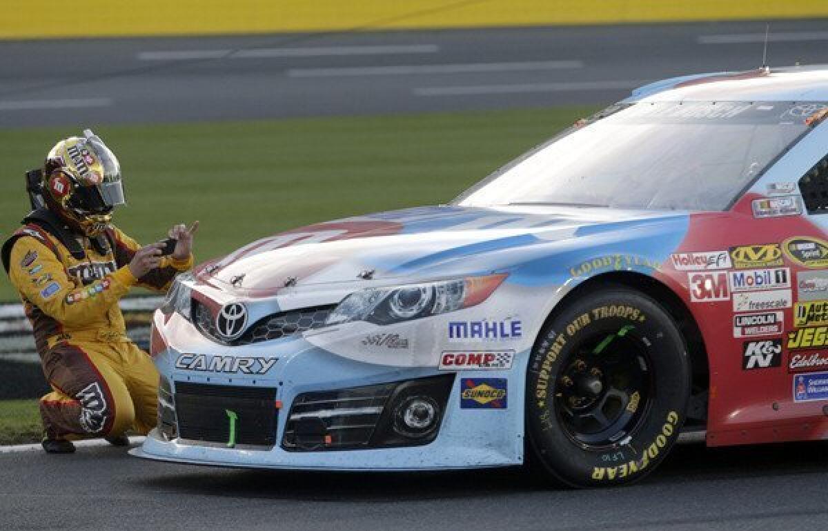 NASCAR driver Kyle Busch takes a photo of his damaged race car with his smartphone after a cable fell across the track at Charlotte Motor Speedway on Sunday during the Sprint Cup Series Coca-Cola 600.