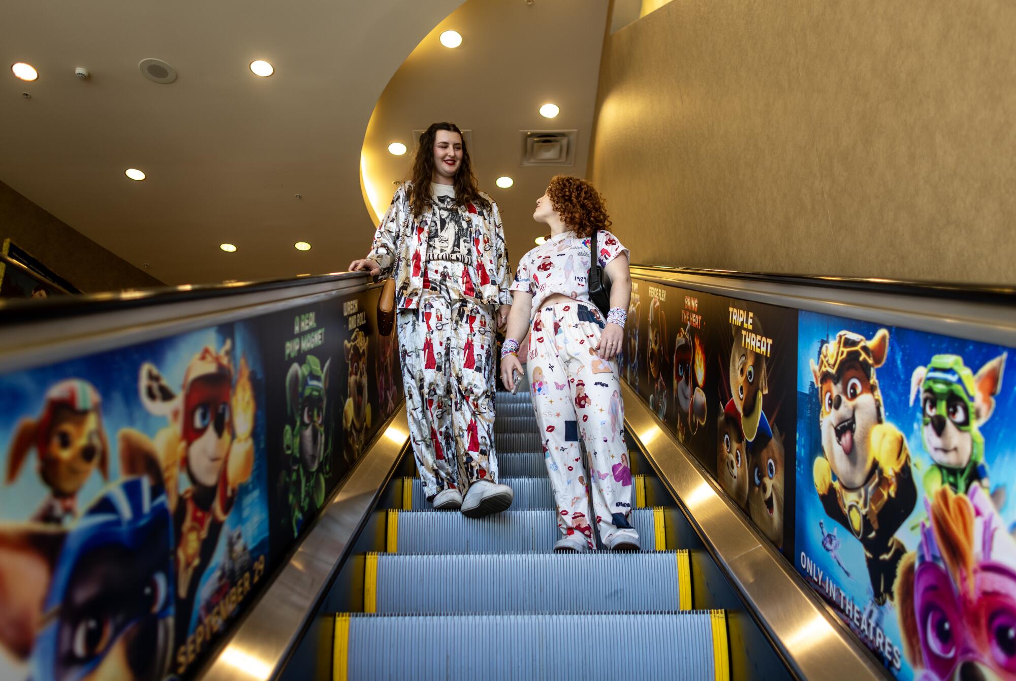  Wearing Taylor Swift pajamas, Kristen Briggs, 25, left, and Ali Zatlin, 25, of Century City, ride the escalator 