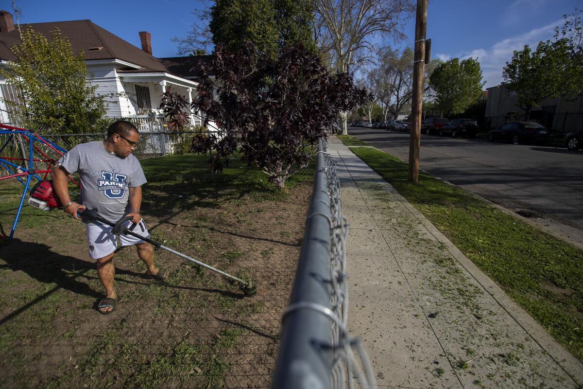 Pao Vang trims the grass at a home he rents in the Lowell neighborhood in Fresno.