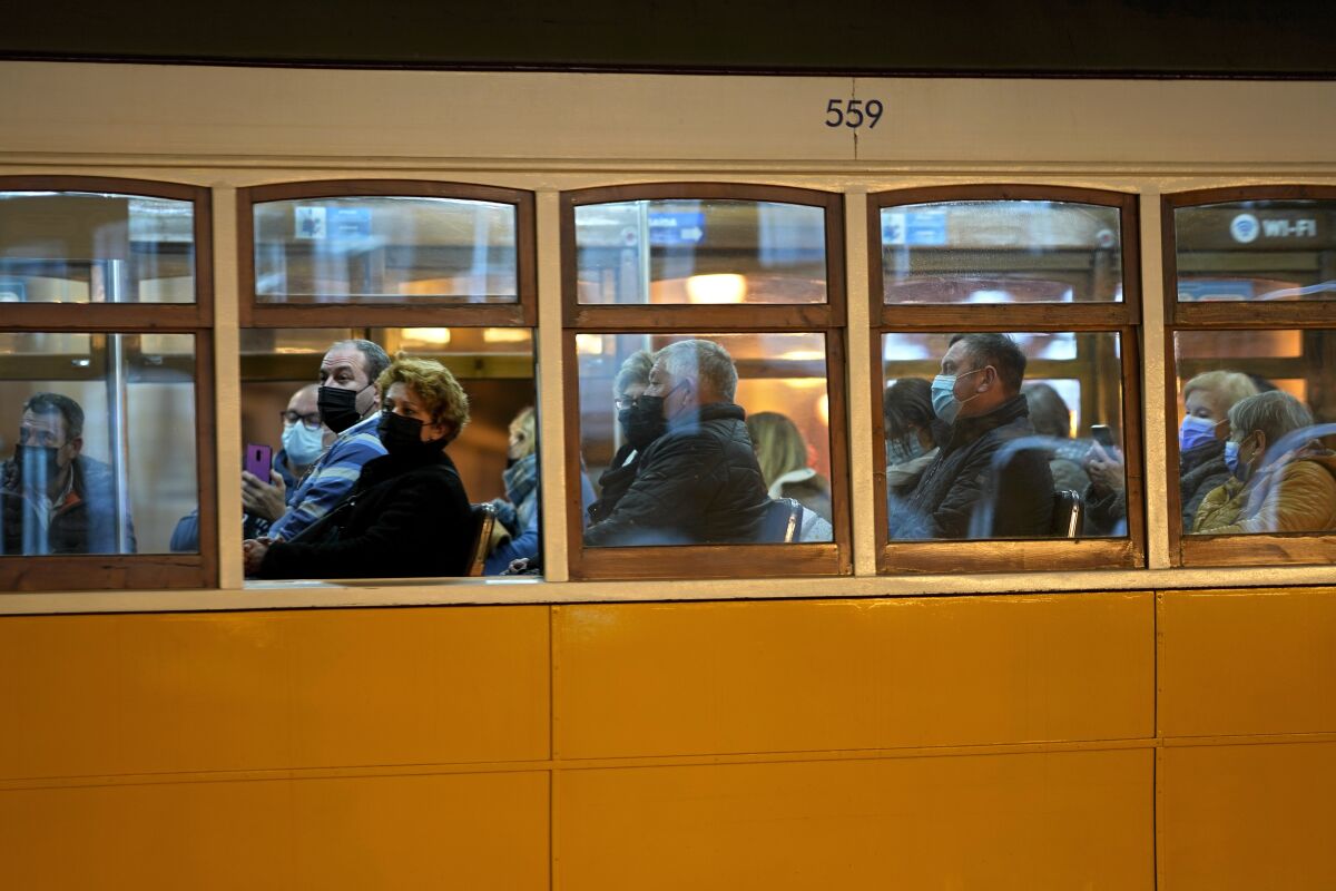 People wearing face masks ride a tram in downtown Lisbon, Monday, Dec. 6, 2021. Despite having one of the highest vaccination rates in Europe, with 86.6% of its 10.3 million people inoculated, Portugal is scaling up its pandemic response amid the emergence of the omicron variant. (AP Photo/Armando Franca)