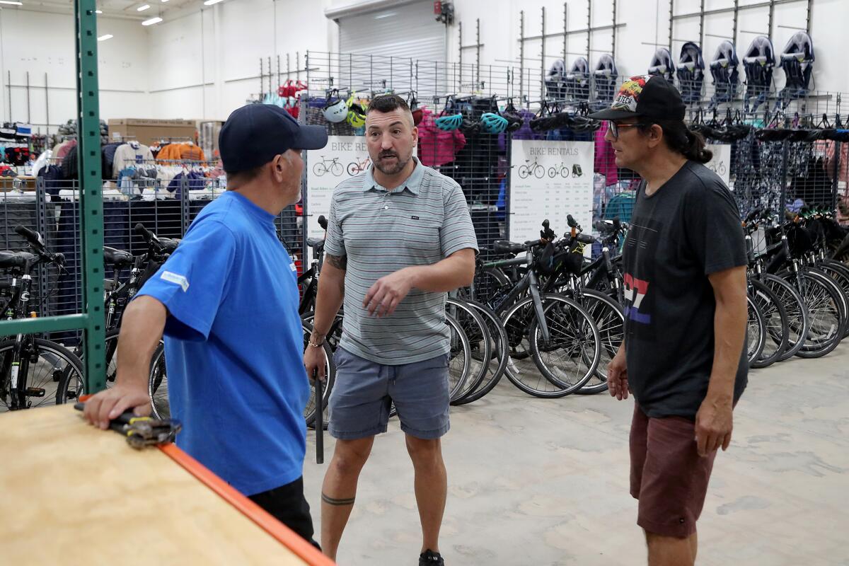 Eden Slezin, center, speaks to repair shop manager Rich Koshimizu and staff member Don Fisher at the new Sports Basement.