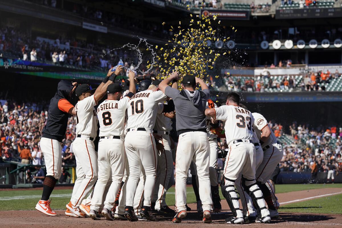 San Francisco Giants players celebrate after Wilmer Flores, hidden, hit a two-run home run during the ninth inning of a baseball game against the Philadelphia Phillies in San Francisco, Sunday, Sept. 4, 2022. (AP Photo/Jeff Chiu)