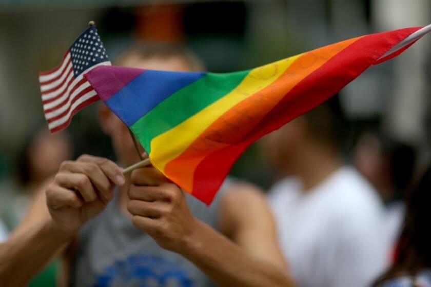 A protester holds an American flag and rainbow flag in front of the Miami-Dade Courthouse in Florida to show his support of LGBTQ couples.