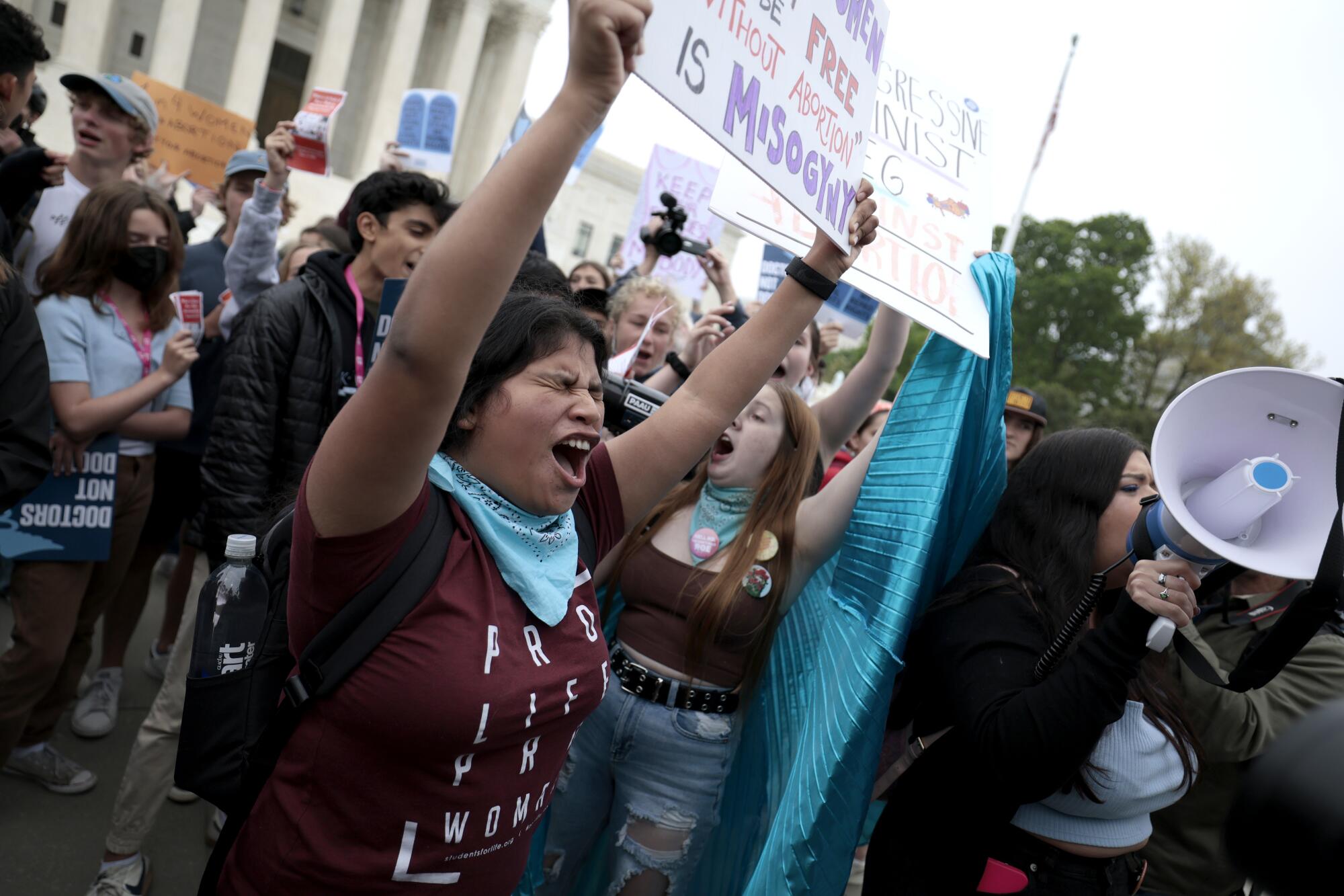 Demonstrators, including one in a T-shirt reading, "Pro life, pro woman," chant in front of the Supreme Court. 