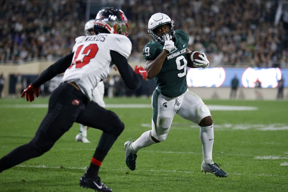 Michigan State's Kenneth Walker III, right, runs for a touchdown against Western Kentucky's Miguel Edwards during the first quarter of an NCAA college football game, Saturday, Oct. 2, 2021, in East Lansing, Mich. (AP Photo/Al Goldis)