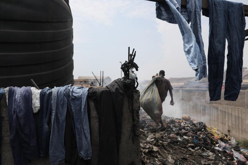 A man walks at a second hand clothes dump site at the Kantamanto Market in Accra, Ghana, on November 15, 2023. Kantamanto market is vast, spanning over 20 acres in the heart of Accra's business district, its stalls dominated by used clothing and shoes from the West and China. Its traders import a staggering 15 million garments a week, according to the OR Foundation environmental group. But roughly 40 percent of each bale ends up as waste, they say, dumped in landfills and often washed into the ocean, causing a public health crisis and harming the environment. Ghana became the world's largest importer of used clothing in 2021, according to the Observatory of Economic Complexity (OEC) data site, with garments worth $214 million shipped mostly from China, the United Kingdom and Canada. (Photo by Nipah Dennis / AFP) (Photo by NIPAH DENNIS/AFP via Getty Images)