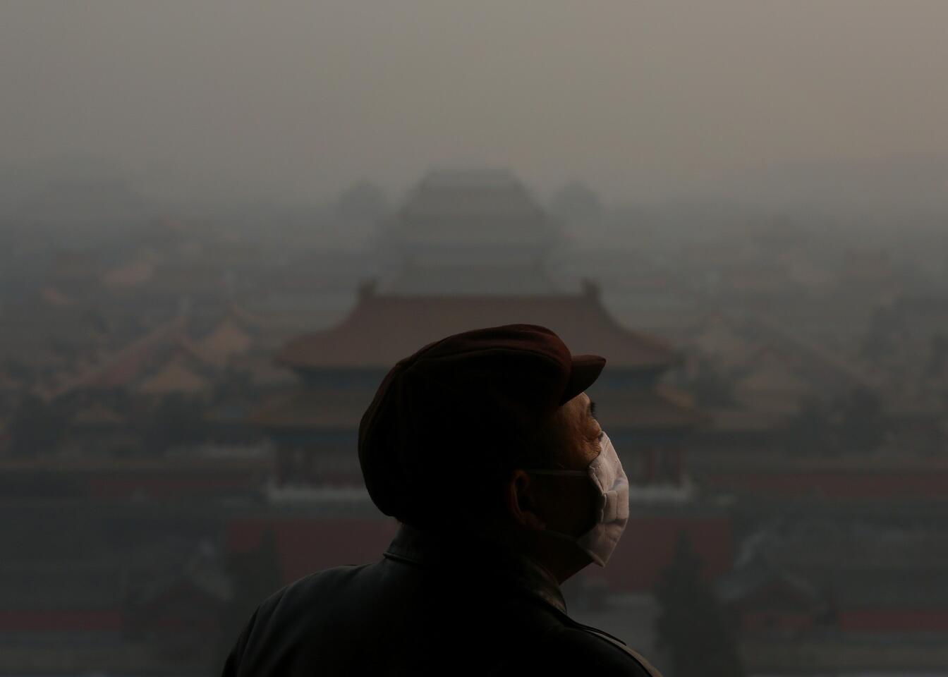 A tourist wearing the mask looks at the Forbidden City in Beijing as pollution covers it Jan. 16. Heavy smog shrouded Beijing as pollution reached hazardous levels days earlier.