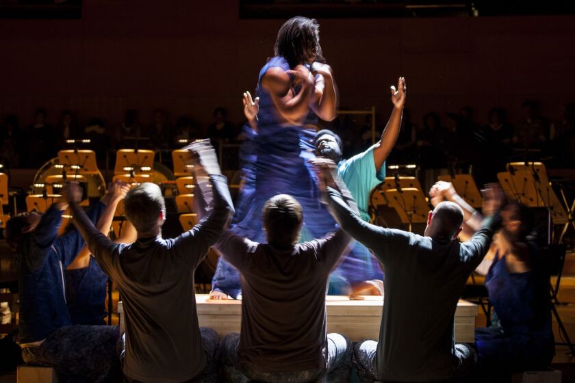 Dancer Anani Dodji Sanouvi is surrounded by the cast during a March 4 rehearsal of John Adams' "Gospel According to the Other Mary," with the L.A. Phil at Disney Hall.