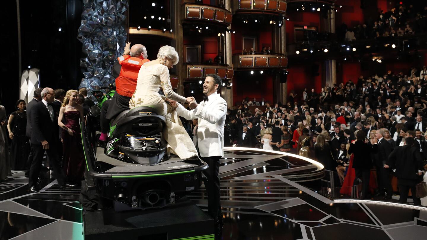 Host Jimmy Kimmel holds onto Helen Mirren, seated on the jet ski won by Mark Bridges, who earned an Oscar in costume design for "Phantom Thread."