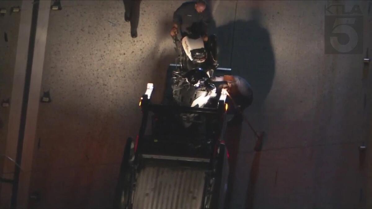 Police officers load the wreckage of a motorcycle into the back of a truck