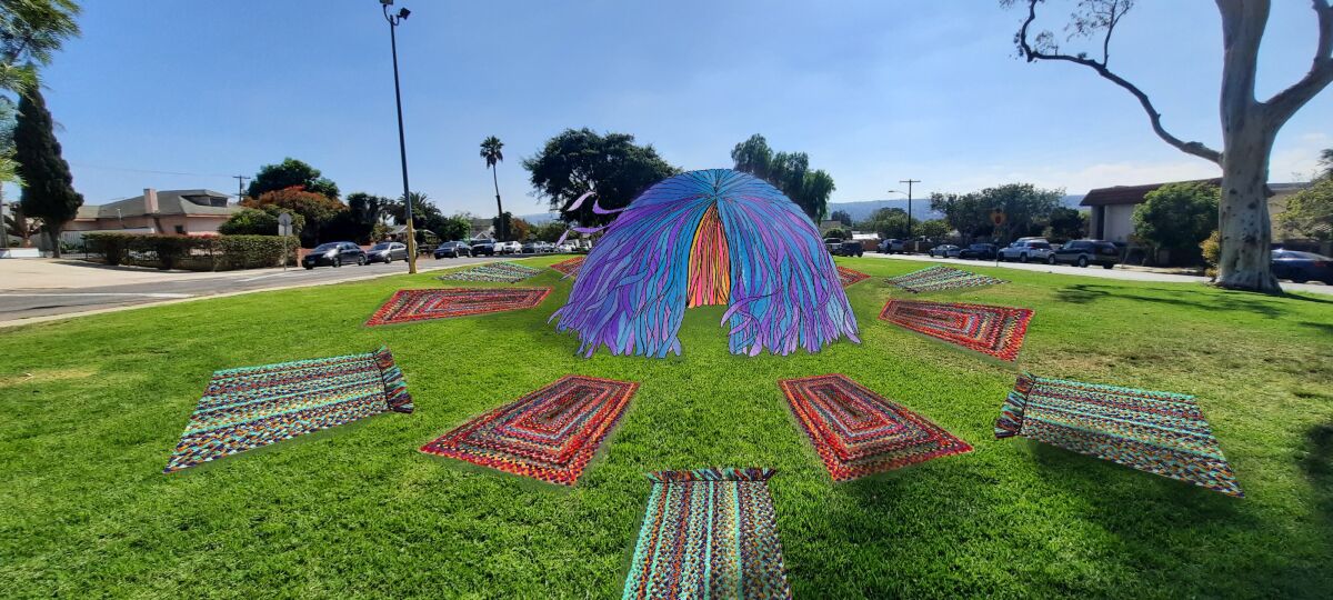A dome-shaped structure and colorful mats on the grass in a city park.