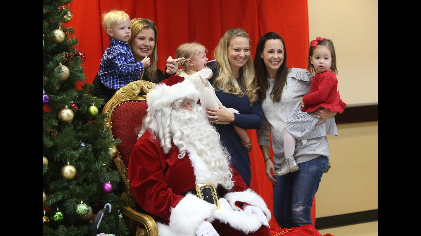 Moms Annie Bower with Tyler, Kelsey Gram with Ansley and Natalie Grasso with Addison get a group picture with Santa Claus during the Breakfast with Santa event at the Newport Coast Community Center on Friday.
