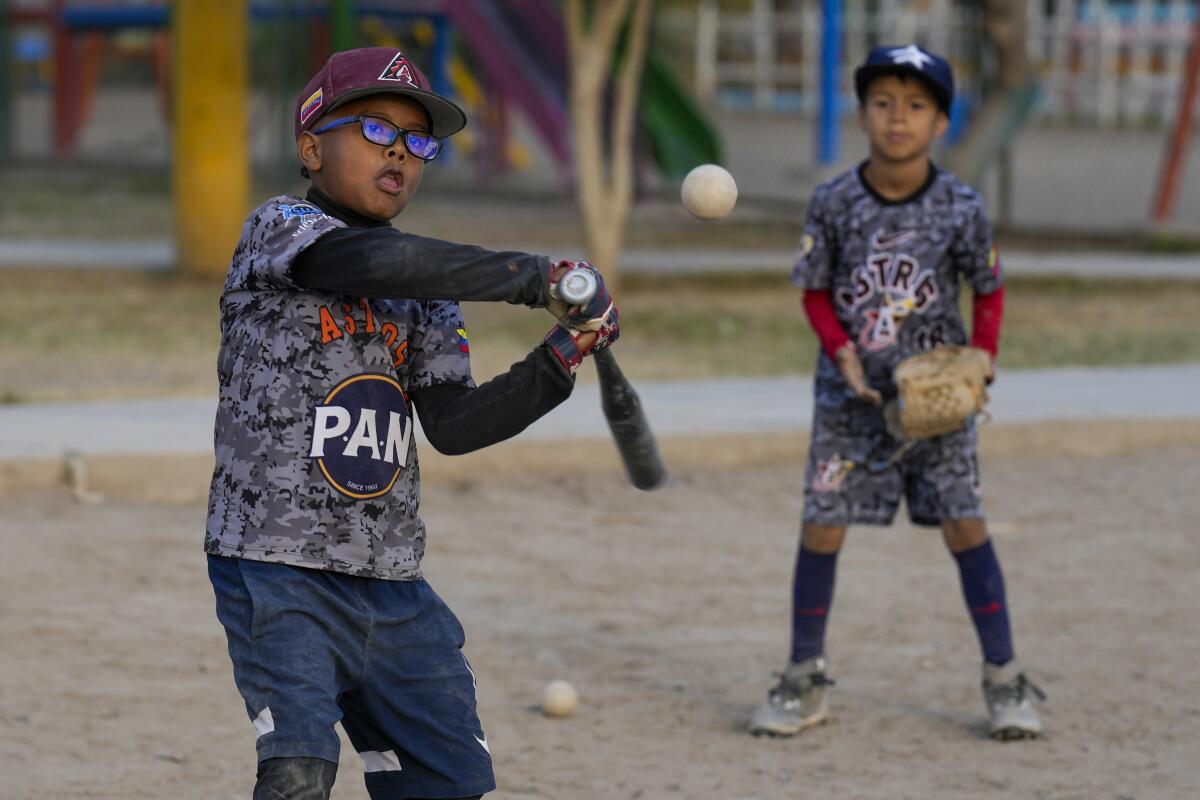 Venezuelan migrant Rodrygo Gil bats during baseball practice in a public park in the Comas area, on the outskirts of Lima, Peru, Thursday, May 9, 2024. Immigrants, mainly Venezuelans, have opened five baseball academies in Peru's capital. (AP Photo/Martin Mejia)